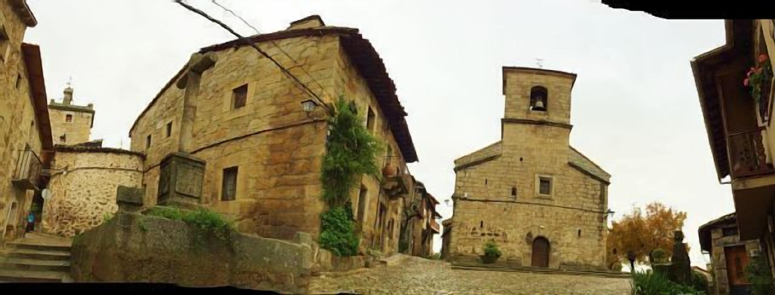 Un edificio de piedra con un campanario y una escalera que lleva a él, sobre una calle adoquinada.