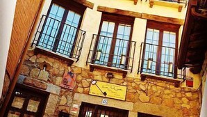 A multi-story building with stone facade, multiple balconies, and a visible sign indicating a restaurant.
