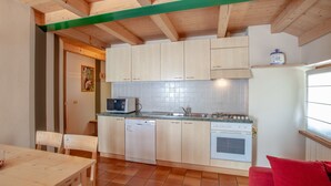 A compact kitchen with wooden cabinets, a built-in oven, and a dishwasher. - Chalet Terme Bormio - REIT (Bormio)