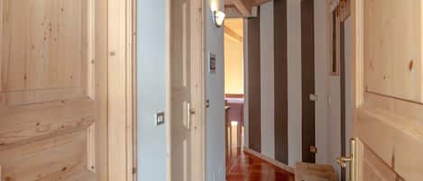 A wooden hallway with tiled flooring and wooden doors.