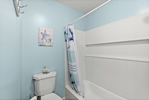 A bathroom with a toilet, a bathtub, and a shower curtain.