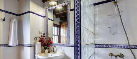 A bathroom with a white sink, mirror, and shower.