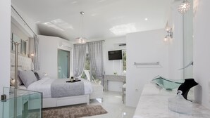 A modern bedroom with a glass shower enclosure, a marble bathroom vanity, and a large bed with a fluffy rug. - Dion Villa (Zakynthos Island)