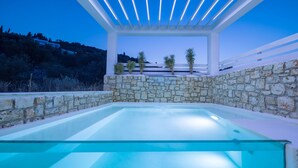 A glass-enclosed infinity pool with a stone wall and a white pergola structure. - Dion Villa (Zakynthos Island)