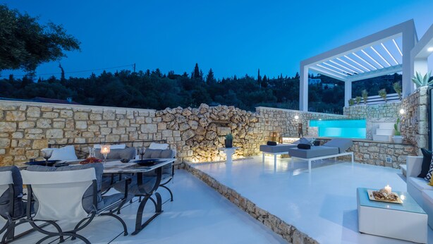A modern outdoor patio with stone walls, a pool, and seating areas. - Dion Villa (Zakynthos Island)