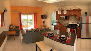 A modern kitchen with a central island, a dining area with a sofa, and a balcony with a view. - Paradise beach front condo with stunning views. (Flexible cancellations) (Antigua and Barbuda)