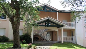 A two-story building with a covered entrance, a staircase, and a tree in the foreground. - Fancy the ocean? 500 m from the beach, wifi fiber, bed linen, terrace, pool, parking (Moliets-Et-Maa)