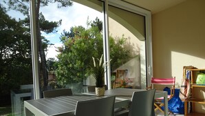 A patio with a table and chairs, a sliding glass door, and a view of trees and a house. - Fancy the ocean? 500 m from the beach, wifi fiber, bed linen, terrace, pool, parking (Moliets-Et-Maa)