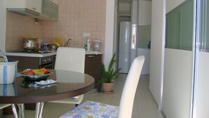 A compact kitchen with a dining area, including a round table, chairs, and a potted plant.