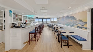 A long dining area with high tables and chairs, a bar on the left, and a large window with a cityscape view. - DAILY ACTIVITIES & LINENS INCLUDED*! Direct Plaza Oceanfront 2BR/2BA with Open Den. (Ocean City)