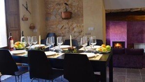 Un comedor con pared de piedra, chimenea y sofá morado.