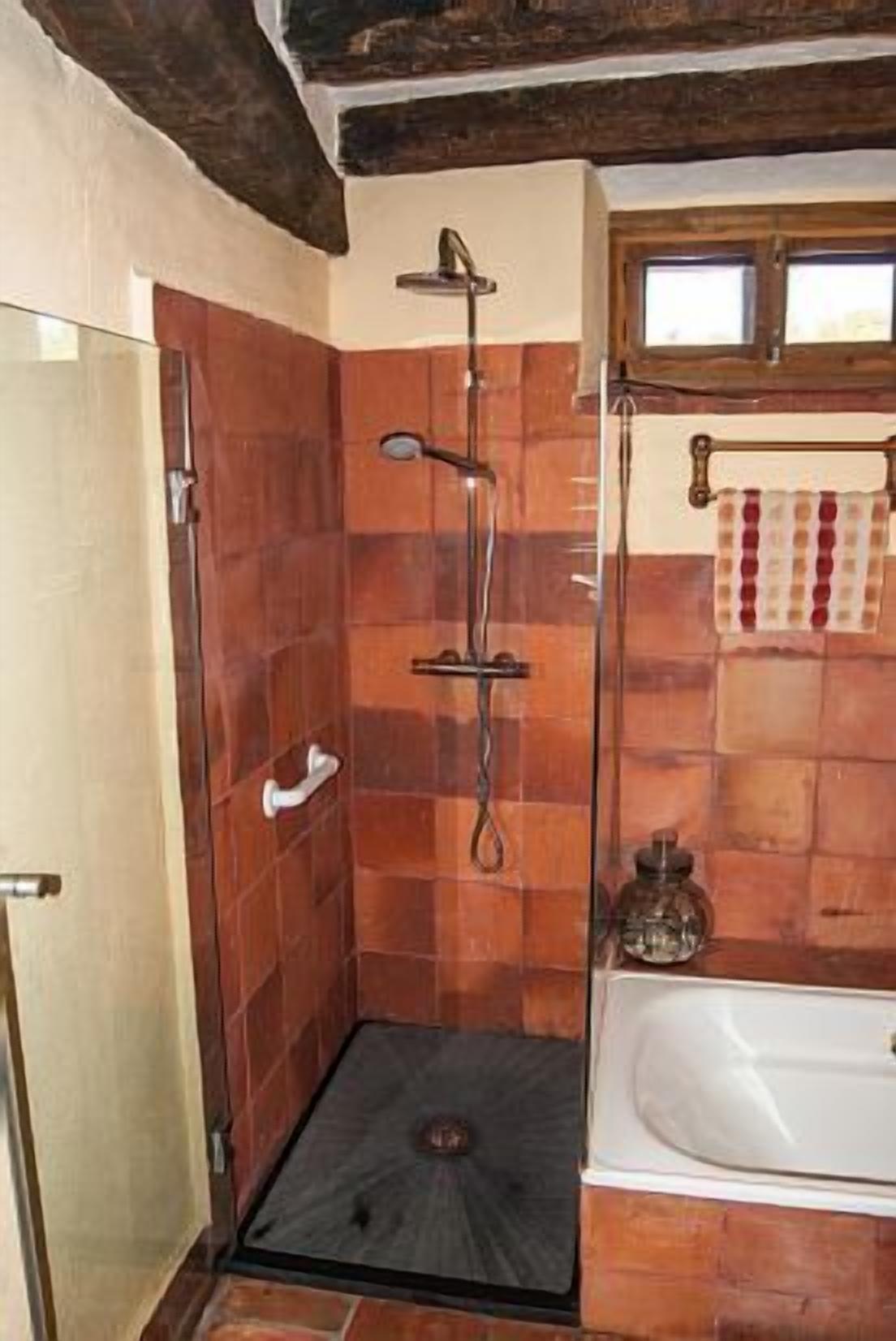 Ein Badezimmer mit Dusche, Badewanne und Fliesenboden.