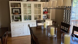 A dining area with a wooden table, chairs, and a cabinet with glass doors containing kitchenware. - Contemporary East Side Townhouse (Providence)