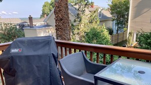 A deck with a grill cover, a chair, and a table. - Contemporary East Side Townhouse (Providence)