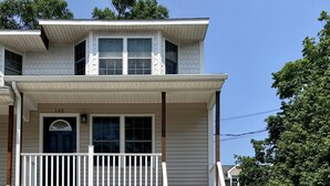A two-story house with a front porch, a garage, and a wooden fence. - Contemporary East Side Townhouse (Providence)