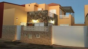 A modern house with a stone facade, a balcony, and a gated entrance.