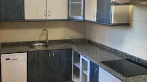 A kitchen with dark cabinets, a dishwasher, a sink, and a stove.