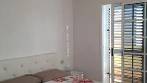 A bedroom with a bed, a ceiling light fixture, and a window with blinds.