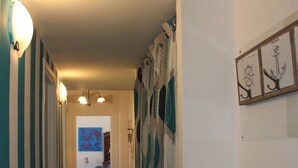 A hallway with patterned curtains, a blue painting on the wall, and a sofa in the background. -  Sunflower Levanto central 100 meters from the sea with views across the valley (Levanto)