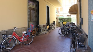 A covered bike parking area with multiple bicycles, a red bicycle, and a door leading to a building. -  Sunflower Levanto central 100 meters from the sea with views across the valley (Levanto)