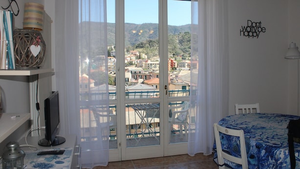 A room with a balcony, a television, a table with a blue tablecloth, and a chair. -  Sunflower Levanto central 100 meters from the sea with views across the valley (Levanto)