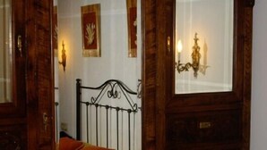 Une chambre à coucher avec un cadre de lit en bois, un lit simple avec un oreiller rouge et une table de chevet.