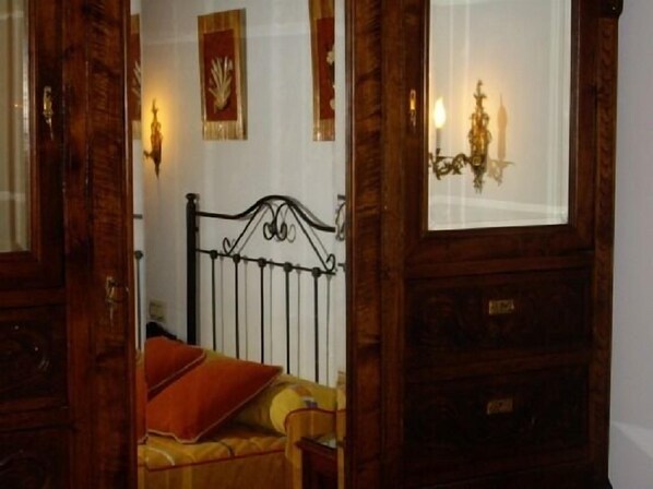 A bedroom with a wooden bed frame, a single bed with a red pillow, and a nightstand.