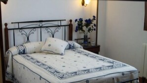 Un lit avec un cadre en métal, une couvre-lit à motifs et un vase rempli de fleurs sur une table de chevet.