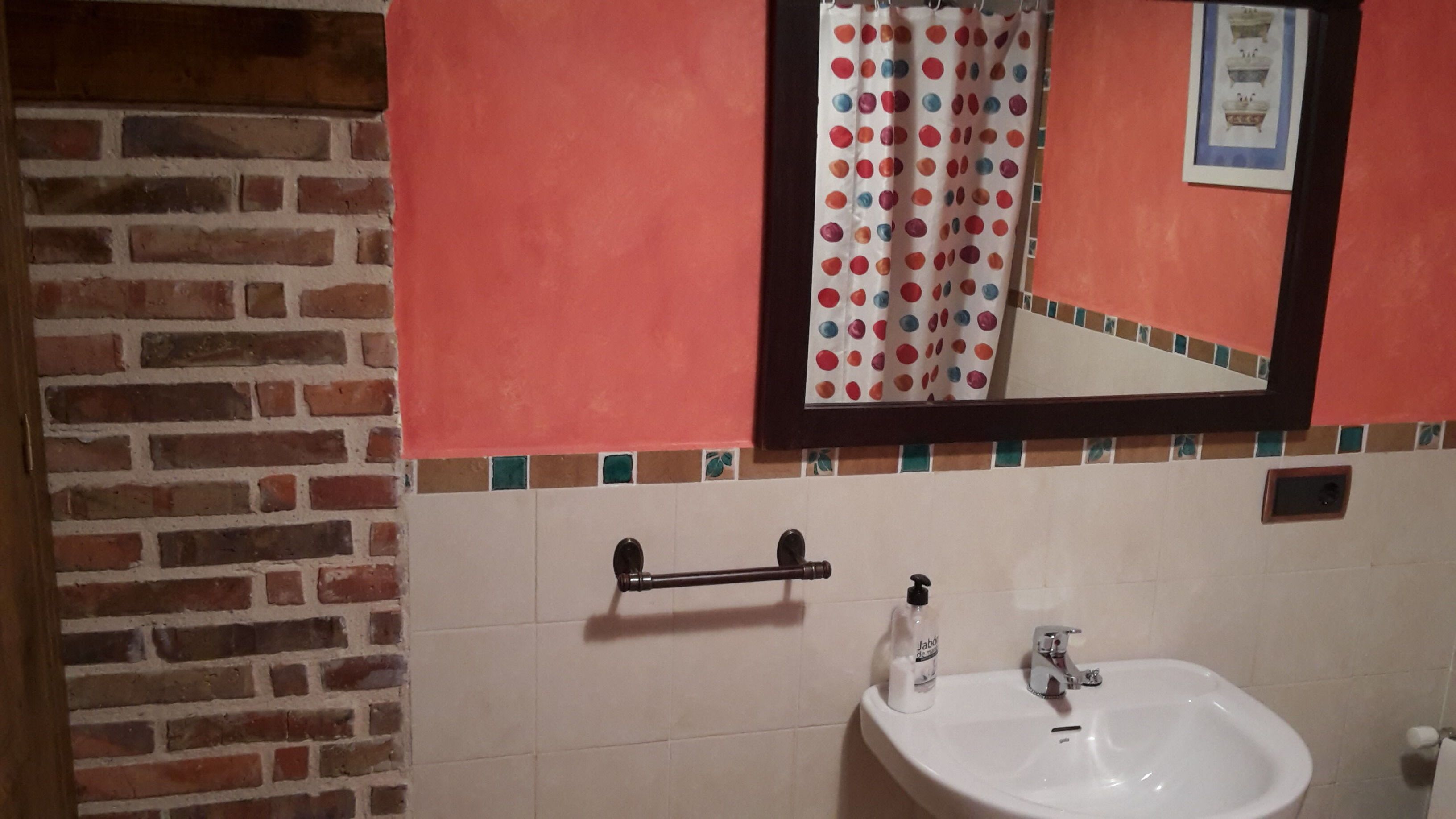 Un baño con un lavamanos blanco, un espejo y una cortina de ducha con estampado de lunares.