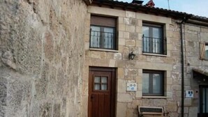 A stone building with a wooden door, windows, and a bench outside. - Cottage (full rental) La Cabaña for 10 people (Ibeas de Juarros)