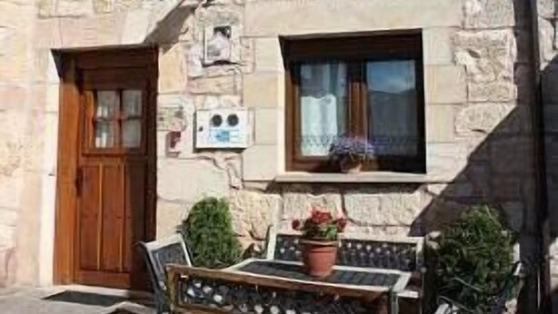 A stone building with a wooden door, two windows, and a bench outside. - Cottage (full rental) La Cabaña for 10 people (Ibeas de Juarros)