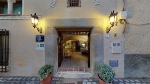 La entrada de un edificio con un arco de piedra, dos macetas y un cartel que indica 'Villa Cornelius' y 'Casas Rurales de Castilla-La Mancha'.