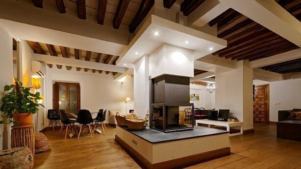 Una sala de estar moderna con chimenea, suelo de madera y una zona de comedor con sillas y mesa.