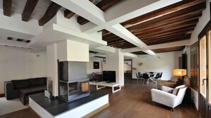 Un amplio salón con una chimenea moderna, un sofá, una mesa de comedor con sillas y una televisión.