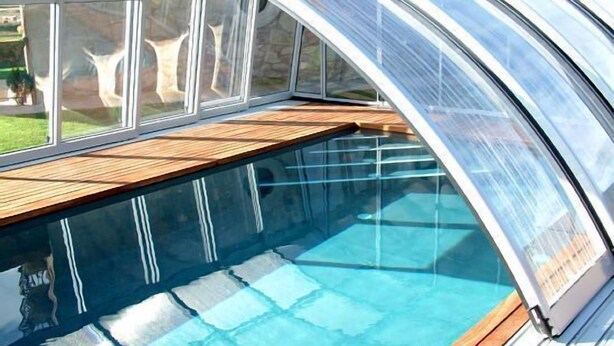 Ein Schwimmbecken mit Holzterrasse und Glasveranda.