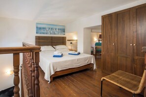 A bedroom with a wooden bed, a chair, a wardrobe, and a painting on the wall.