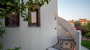 A curved staircase with a patterned rug leading to a door with a light fixture above it. - Spacious sea view studio  ATHENA  for 2-3 persons in Rhodes - Ialysos (Rhodes)