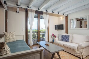 A room with a bed, a sofa, a table, a TV, and a balcony with a view.