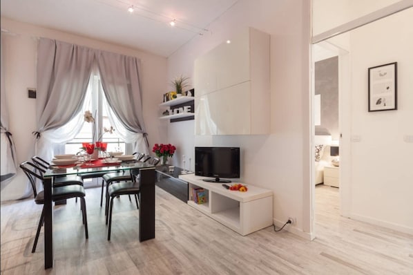 Enjoy a spacious living area with a flat-screen TV and dining space featuring a glass-top table and comfortable seating.
