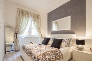 A bedroom with a bed, bedside table, lamp, and a window with curtains. - Lovely apartment in center city (Verona)