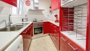 Una cocina moderna con armarios rojos, electrodomésticos de acero inoxidable y un horno empotrado.
