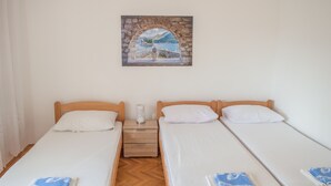 A room with two single beds, a wooden nightstand with a lamp, and a painting of a landscape on the wall. - Risan Apartment, Boka Bay (Risan)