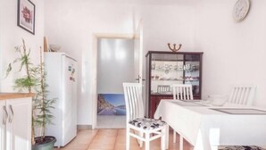 A dining area with a table, chairs, a refrigerator, and a cabinet with glass doors. - Risan Apartment, Boka Bay (Risan)