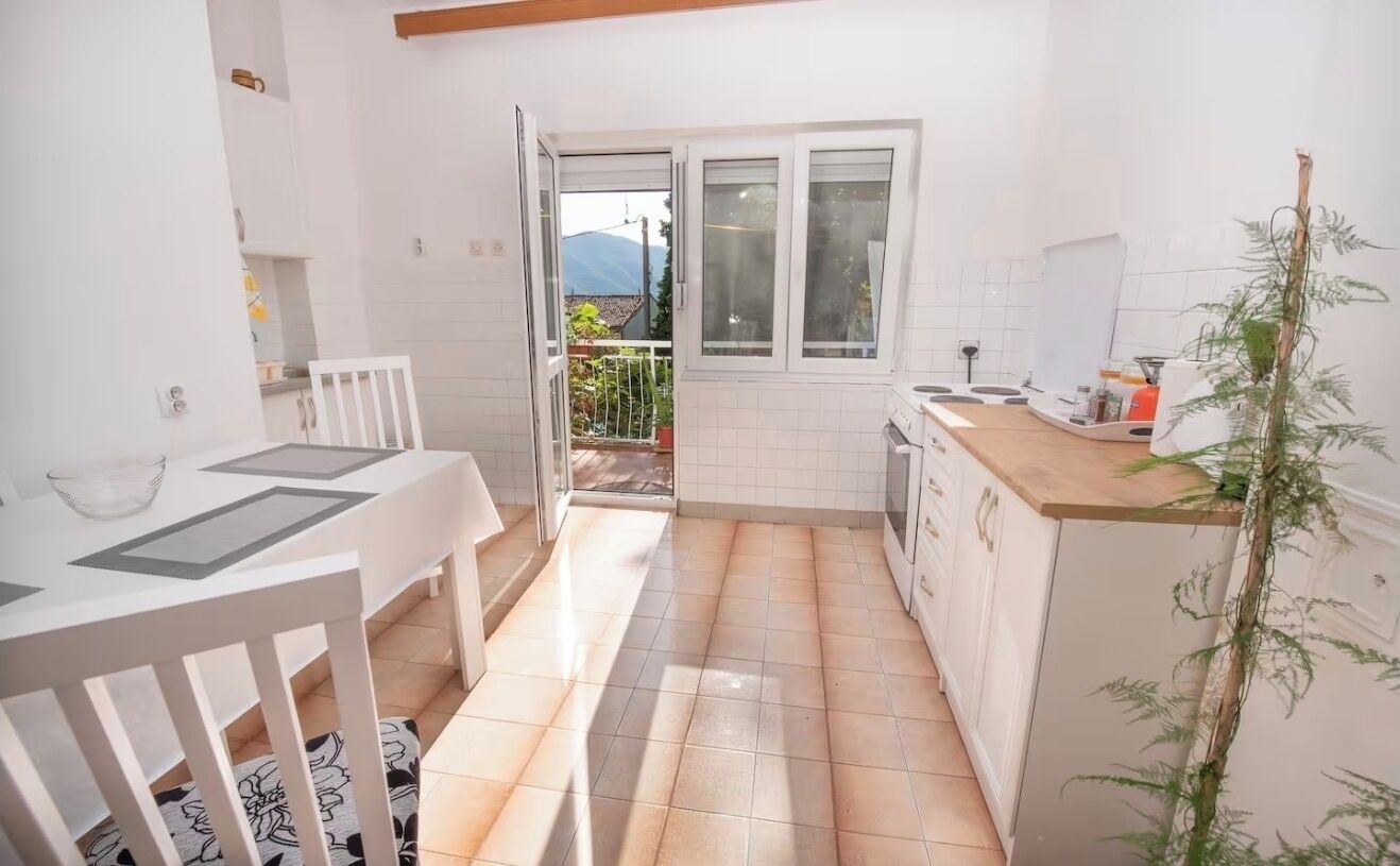 A small kitchen with a dining area, a window with a view, and a plant.