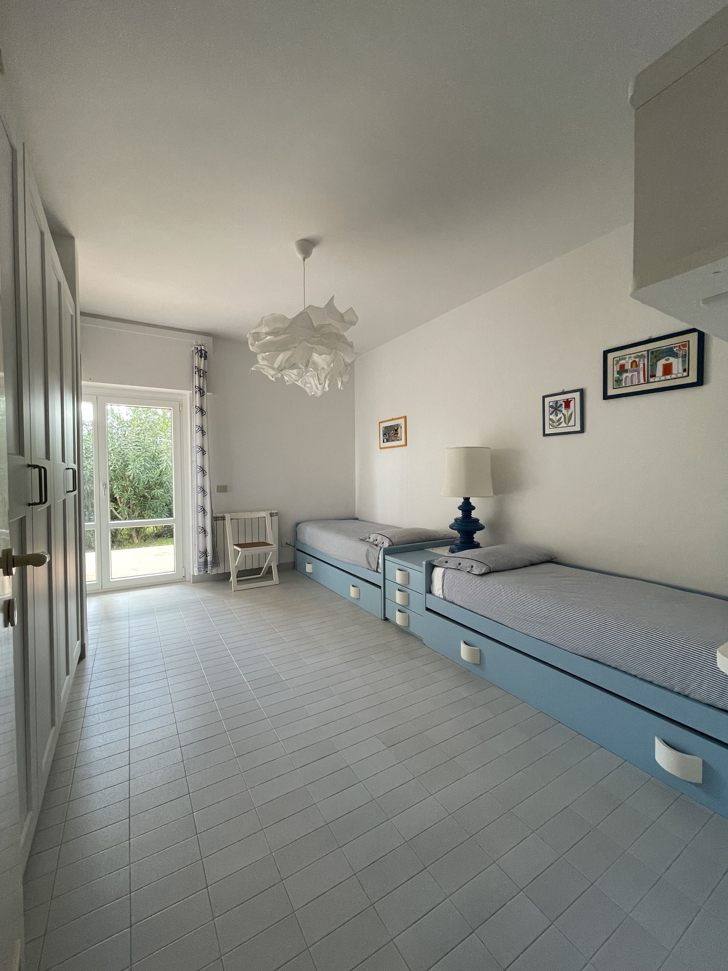 Un dormitorio con cama, mesita de noche y ventana con cortinas.