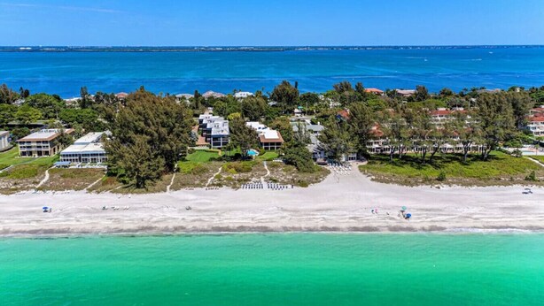 An aerial view of a coastal resort with beachfront properties, a sandy beach, and a clear blue ocean. - Sea Grape Inn #2- Beachfront Property (Longboat Key)