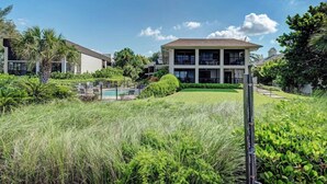 A modern building with a pool, surrounded by lush greenery and palm trees. - Sea Grape Inn #2- Beachfront Property (Longboat Key)