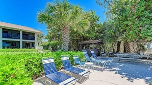 A poolside area with lounge chairs, a gazebo, and lush greenery. - Sea Grape Inn #2- Beachfront Property (Longboat Key)