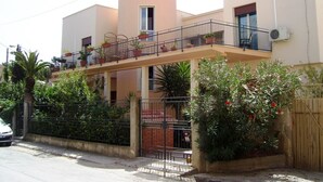 A two-story building with a balcony, surrounded by greenery and a gated entrance. - Villa Gelvi. Apartment in villa 2 minutes from the sea (wi fi, solarium, games) (Castellammare del Golfo)