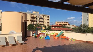 A rooftop playground with play structures, a basketball hoop, and a seating area with chairs. - Villa Gelvi. Apartment in villa 2 minutes from the sea (wi fi, solarium, games) (Castellammare del Golfo)